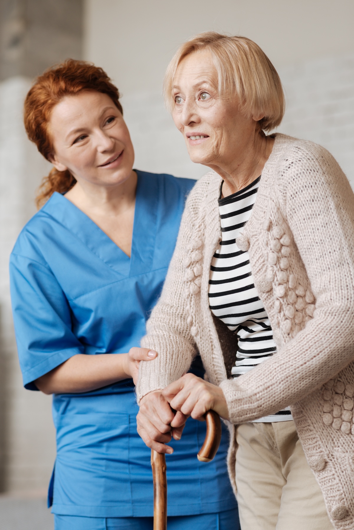 Prominent caring nurse helping her patient standing up recrutement aide-soignant